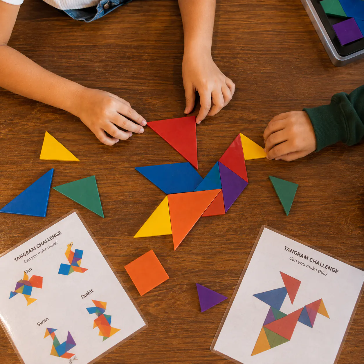 A child’s hands arranging brightly coloured tangram pieces